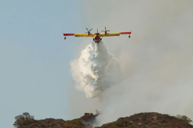 GLENDALE, CA - SEPTEMBER 9: A CL-215 "Super Scooper" air tanker drops a white cloud of water instead of the usual red fire retardant used by other air bombers at a wildfire September 9, 2002 in Glendale, California. The "Super Scooper," which scoops up water as it flies across a lake surface, is popular among politicians but some fire bosses are not yet sold on the new aircraft as a cost-effective means of suppressing fire. Homes were threatened today but none were lost in the 800-plus acre wildfire burning in the Los Angeles suburbs of Glendale and Burbank. Containment of the fire is set at 20 percent. (Photo by David McNew/Getty Images)